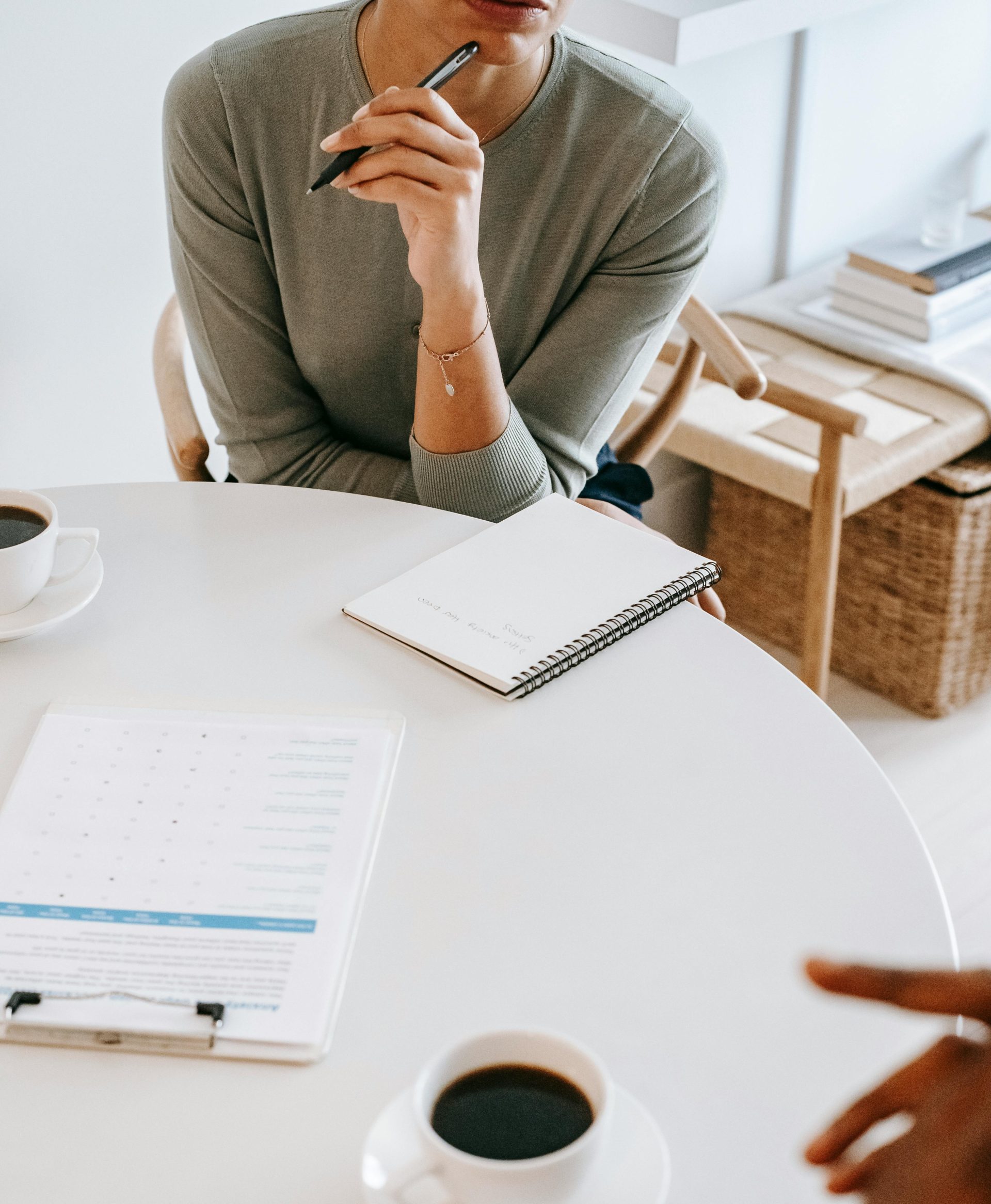 High angle crop professional female psychotherapist with pen and notepad listening attentively to client during psychotherapy session in light studio