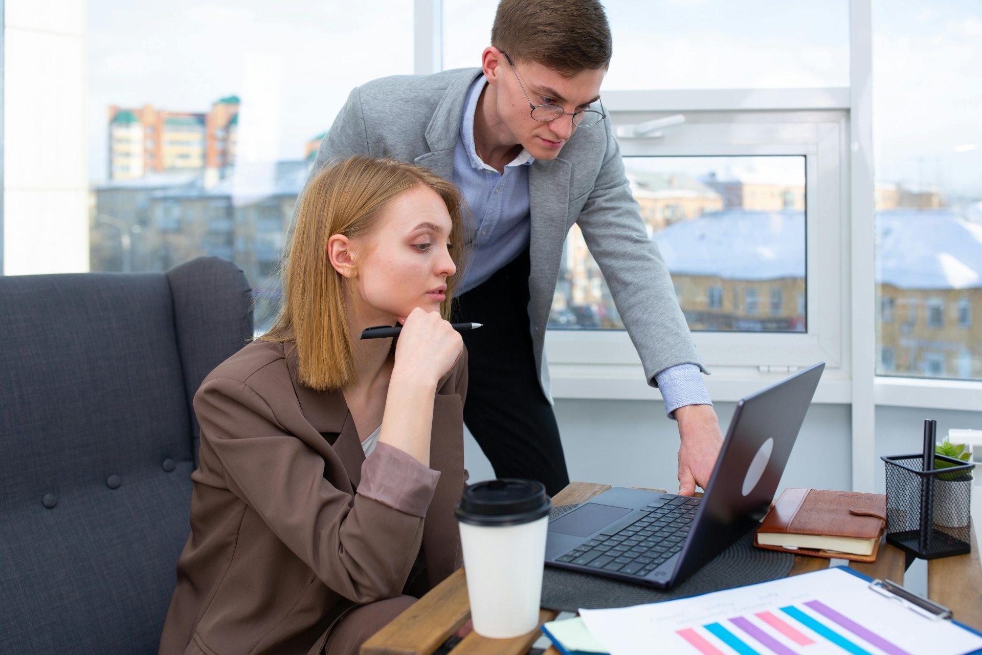 Business professionals collaborating on a project using a laptop in a modern office setting.