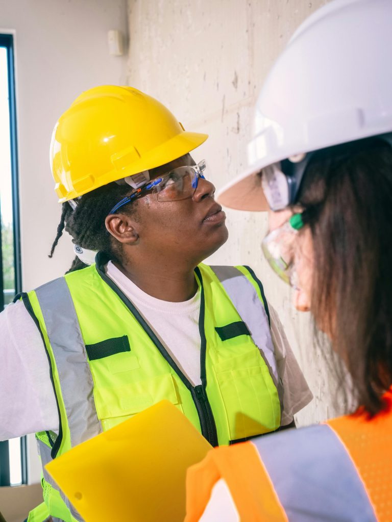 Two engineers in safety gear inspect a construction site, ensuring compliance and safety.